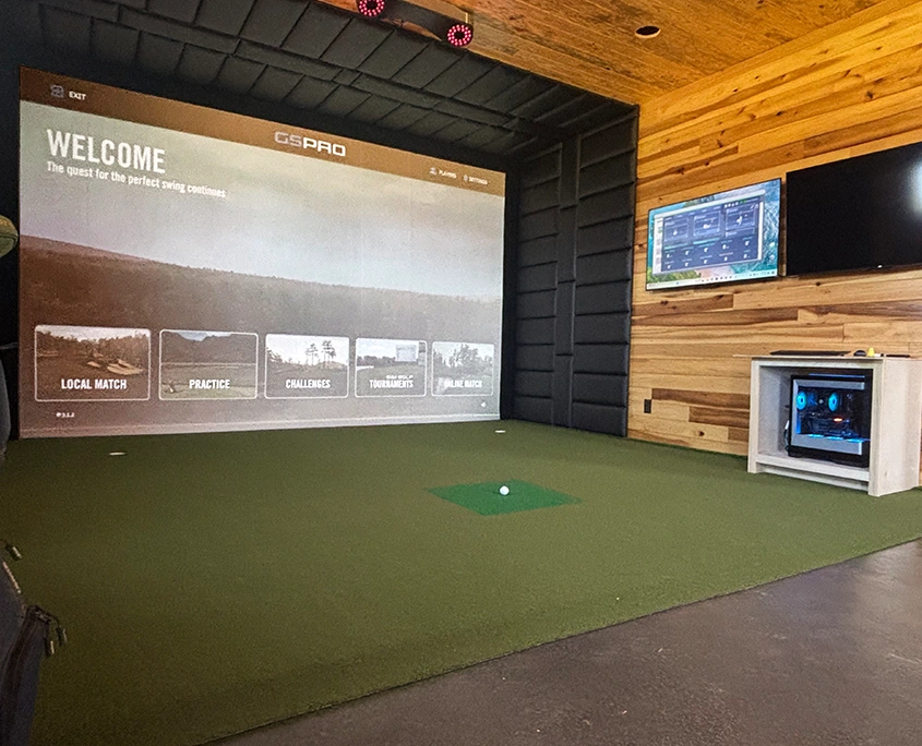 Indoor golf simulator with impact screen, turf, and cedar wall built by Upright Build Co.